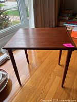 Full view of vintage teak rectangular bunching table from a slight angle showing wood grain and tapering legs.