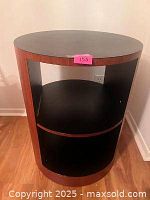 Front view of drum table showing black top, veneer sides, and open shelves