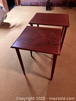 Two teakwood bunching tables placed on carpeted floor showing wood grain and tapered legs.