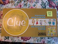 Top view of the vintage 1960 Parker Brothers Clue game box with yellow background and fingerprint graphic, showing lot number sticker.
