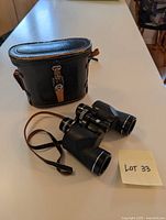 Binoculars and carrying case placed on table shown from an angled view