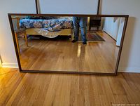Full view of rectangular mirror showing wooden frame and reflection of room.