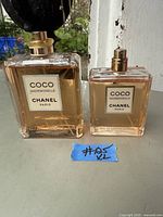 Two full bottles of Coco Chanel Mademoiselle Eau de Parfum Intense, one large and one smaller, displayed side by side on a windowsill with a blue note labeled #25
