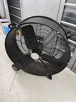 Side angled view showing front grille, blades, wheels underneath, and handle for carrying.