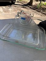 Photo showing two Pyrex rectangular clear glass baking pans stacked and one Pyrex measuring cup on top