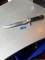 Hunting cutter knife on a light-colored surface showing the full length and handle