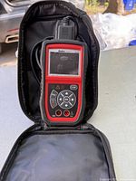 Handheld Autel AL439 diagnostic tool with attached cable inside an open soft black carrying case embroidered with Autel logo.