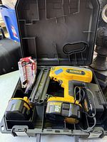 Overview of open carrying case showing nailer, batteries, charger, nail packs.