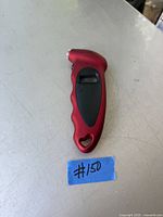 Photo of a red and black digital automobile tire pressure gauge with a digital display and ergonomic grip.