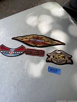 Four Harley Davidson patches on a white table outdoors showing design and size.