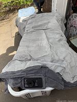 Full length view of the deflated air mattress made by Intex with a light and dark grey top and side fabric cover.