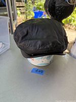 Front view of black leather cap showing stitched panel design and soft structured shape.