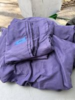 Folded purple sheets set displayed on a surface in natural outdoor lighting. The fabric shows slight creasing and texture.