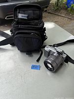 Camera body with attached SEL1855 lens next to camera case