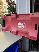 Side view of the Torin Big Red creeper showing the red molded plastic body and part of the black headrest.