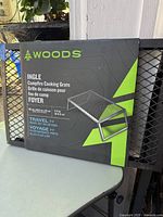 Photo of box packaging showing Woods brand and Ingle campfire cooking grate model with travel tagline.