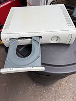 White Xbox 360 console with disc tray open showing front detail and top air vents.