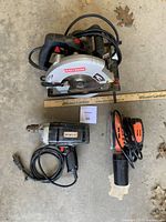 Three power tools laid on concrete floor: Craftsman circular saw on top, Craftsman drill below left, and Tacklife palm sander below right.