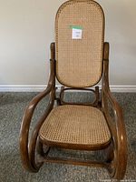 Front view of bentwood rocking chair showing cane seat and backrest with curved wooden arms and base rocker supports.