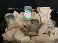Bin containing approximately 15-20 half-pint vintage Crown canning jars with metal lids and packing paper.