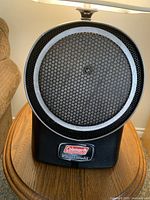 Front view of black Coleman Power Cat portable propane catalytic heater showing circular catalytic element and branding plate