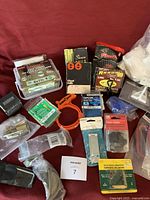 Overview of most miscellaneous hardware items including nails, clamps, staples, screws, hooks and small hardware pieces in their packages and boxes arranged on a surface.
