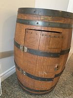 Full view of oak barrel cabinet with metal bands, door with latch, and wheels
