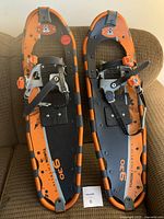 Pair of Yukon Charlie's snowshoes with orange and black metal frames and binding straps.