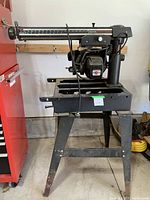 Side view of the full radial saw with stand showing overall condition and structure.