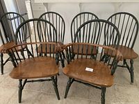 Six Windsor style farmhouse chairs including two with arms and four armless, with visible surface wear on armchairs.