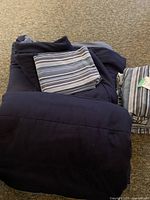 Photo showing two navy blue reversible comforters folded with blue striped sheets on top and beside them