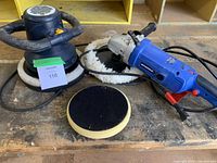 Overall view of Simoniz polisher with attached fluffy pad, foam pad, and random orbit car washer laid on wooden surface.