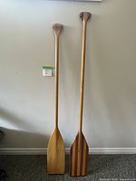 Front view of both solid wood canoe oars showing full lengths and paddle widths