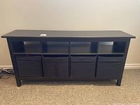 Front view of black storage unit with four baskets in lower compartments and open upper cubbies.