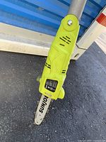 Close-up of the saw blade and motor housing showing the SunJoe branding and control label on green housing attached to the pole saw blade.