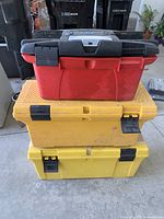 Set of three toolboxes stacked, red Rubbermaid on top, yellow Rubbermaid in middle, yellow Mastercraft at bottom.