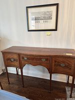 Front view of the mahogany sideboard showing serpentine front, two center drawers with antique brass pulls, two curved side cabinet doors with inlaid wood, tapered legs with carvings.