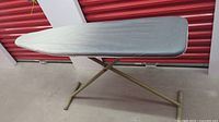 Side angle view of the full ironing board showing the metal frame and grey cover