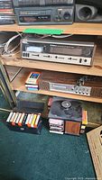 Wide view of the shelving unit with Webcor and Concerto 8 track players, and boxes of 8 track tapes on floor and shelf.