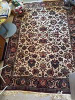 Full view of Persian style area rug showing floral medallion design, cream center, and dark border with floral and geometric details.