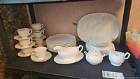 Overall view of cups, saucers, plates and platter arranged on shelving