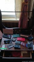 Full view of all wallets, pouches, card holders, and sunglasses arranged on a small table in front of a window.