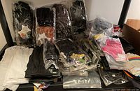 Overview of assorted leather and fabric fingerless gloves laid out on a shelf, some in plastic packaging.