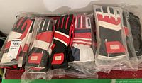 Eight lined leather gloves mostly in original plastic bags with red, black, and white color patterns