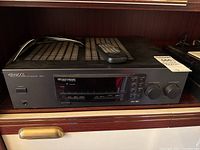 Full view of Kenwood 106VR audio-video surround receiver with remote on top.