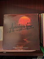 Front cover of Apocalypse Now soundtrack LP showing orange sun and silhouetted palms with title text