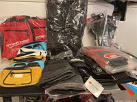 View of multiple fanny packs, black leather gloves, knee pads, and other accessories arranged on table