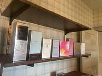 Eight unopened perfume boxes lined up on a shelf, showing a variety of brands and colorful packaging.