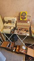 Overview of sewing machine on folding table with wicker-look basket and scissors arrayed