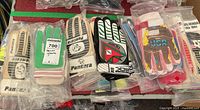Gloves stacked side by side showing Pantera and other branded gloves in plastic bags with various colored designs